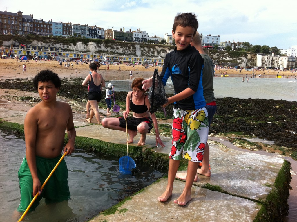 Justin out crabbing with buddies. The tide change here is severe, about 100 yards of sand and rocks - all chalk and flint - appear at low tide. The young kids all have what look like butterfly nets which they use with 'bait bags' of bacon to catch small crabs.